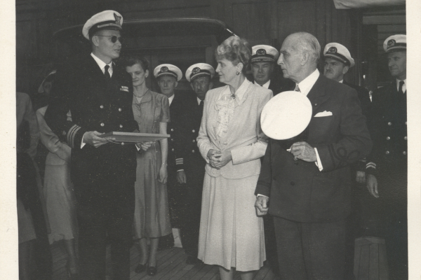 Black and white photo of Captain Skinner presenting a certificate to Marjorie Post and her husband, Joseph E. Davies.