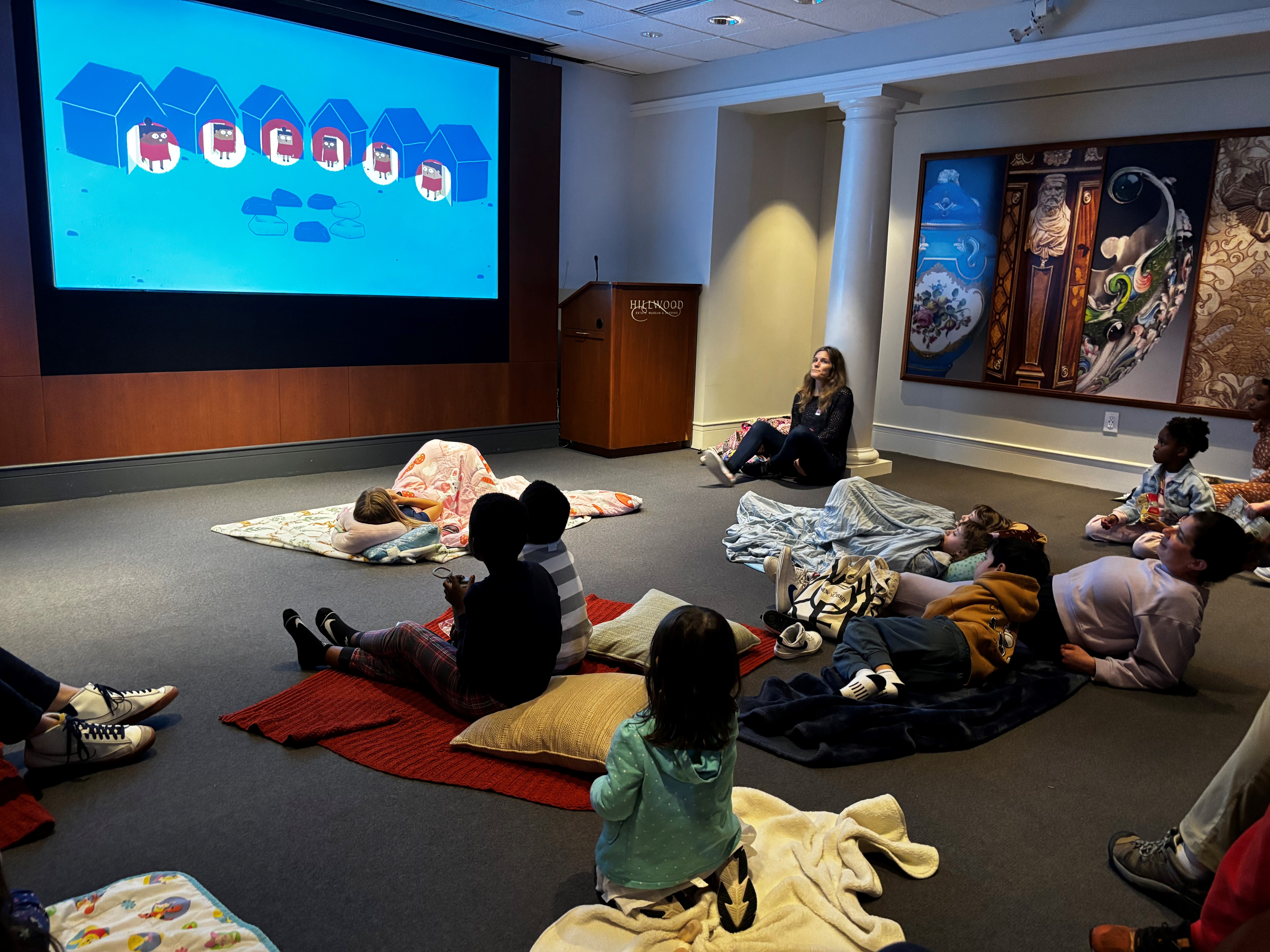 Families snuggled on blankets and pillows watching movie