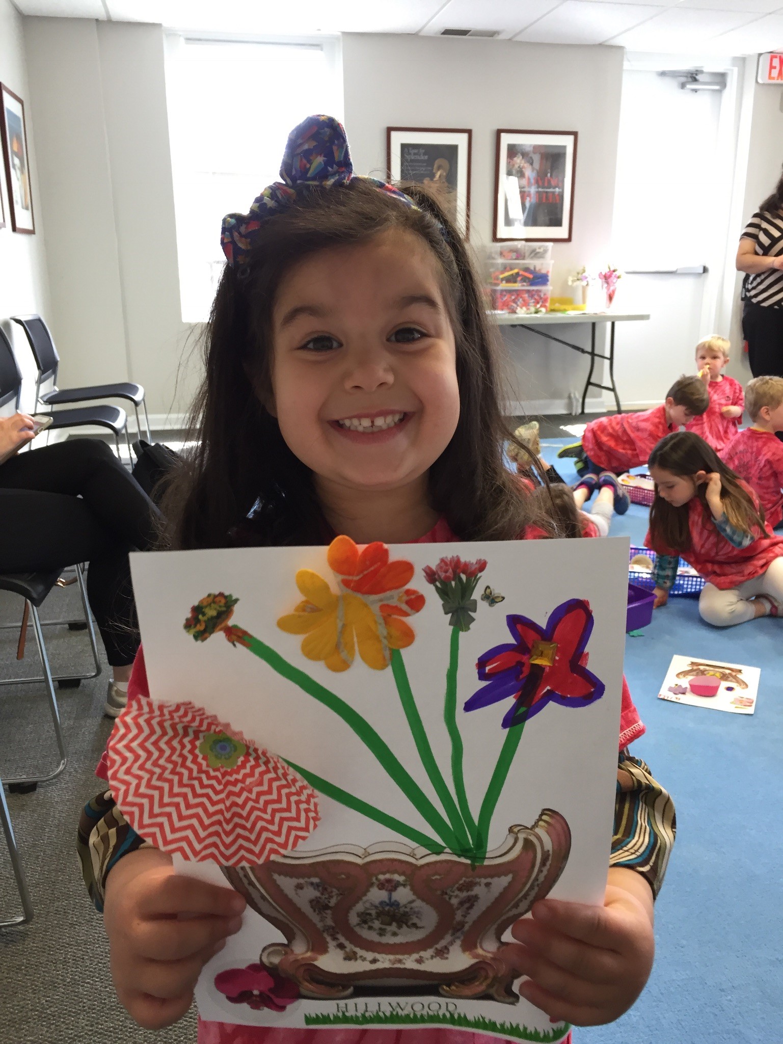 A preschooler proudly holds up her colorful flower picture.